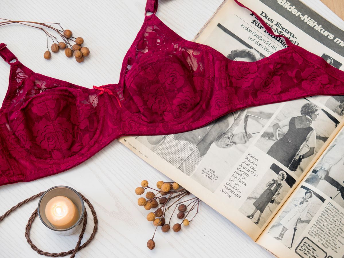 A burgundy lace underwire bra laid flat, showing the curved wire line running under both cups
