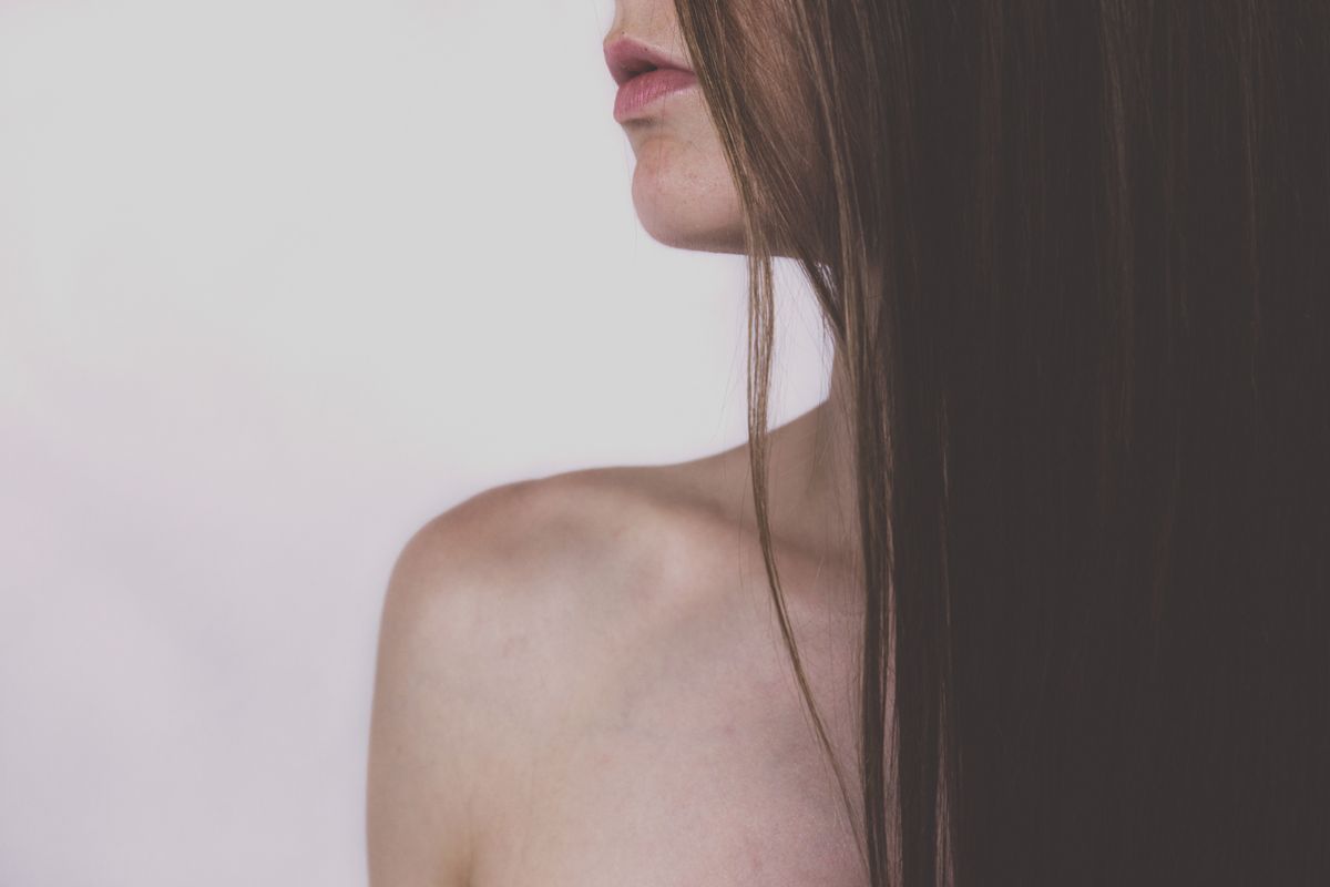 A close-up of a woman caring for the skin on her shoulder where a bra sits