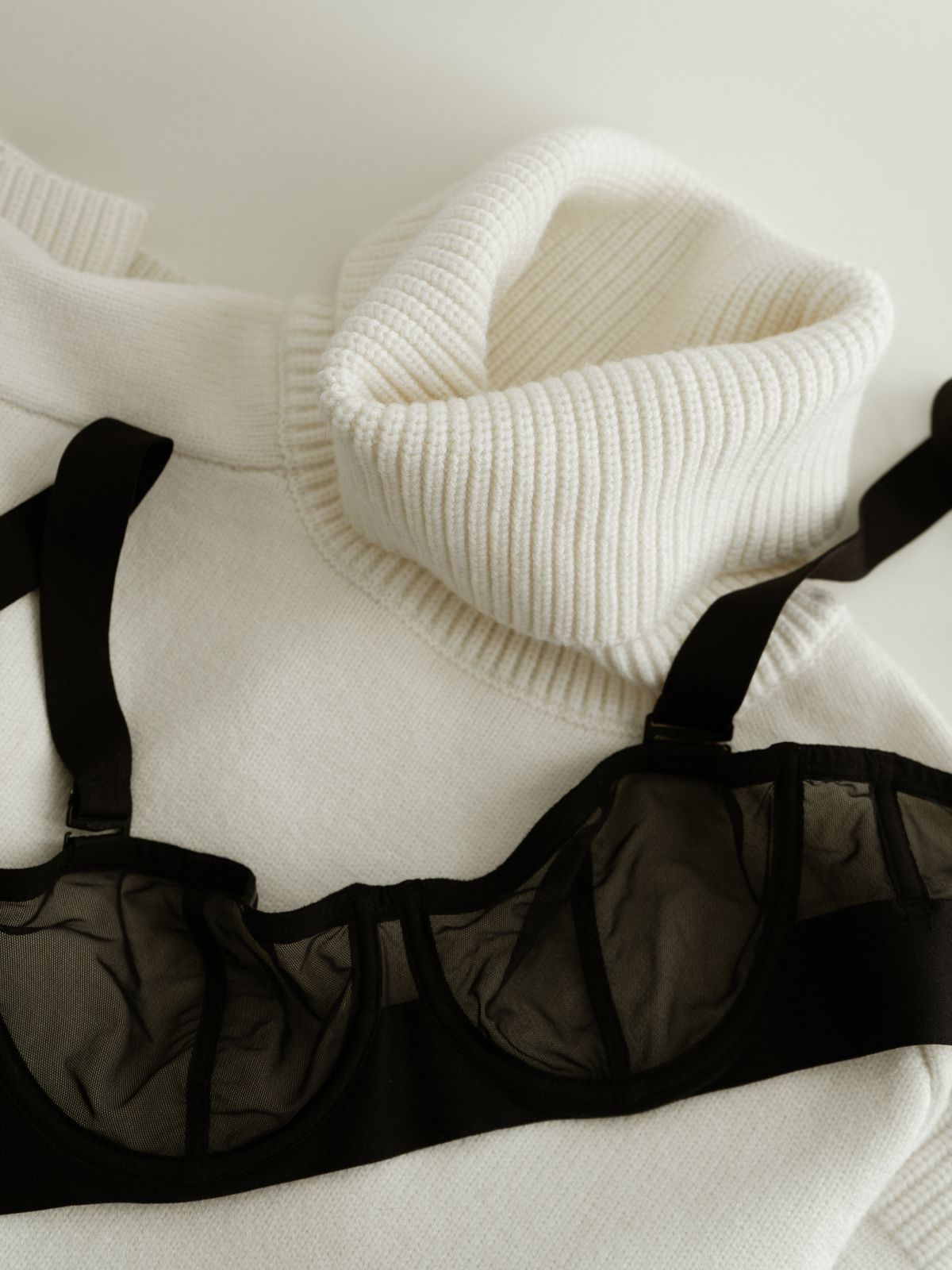 A black sheer underwired bra laid flat, showing a narrow centre gore joining the two wired cups