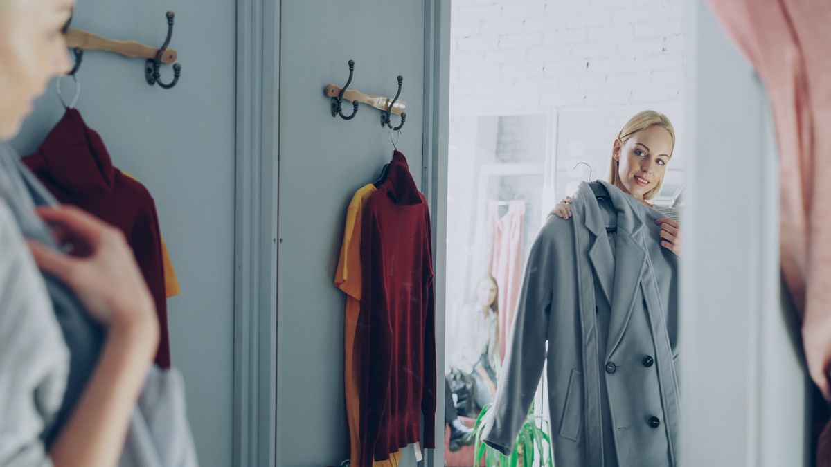 A woman checking the fit of a garment in a fitting room mirror