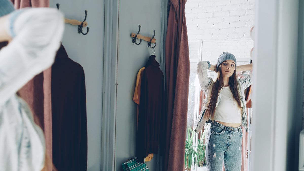 A woman checking how a garment fits in a dressing-room mirror