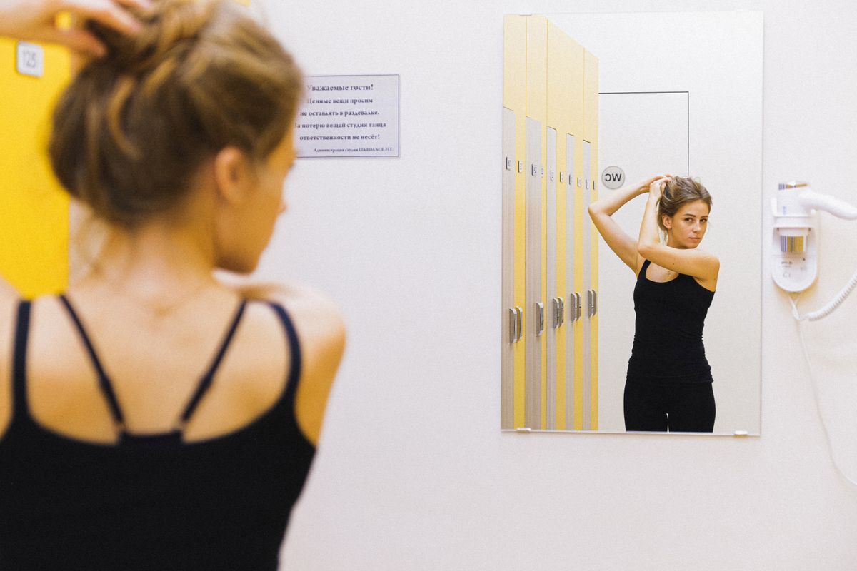 A woman checking how clothing fits in a changing-room mirror before buying