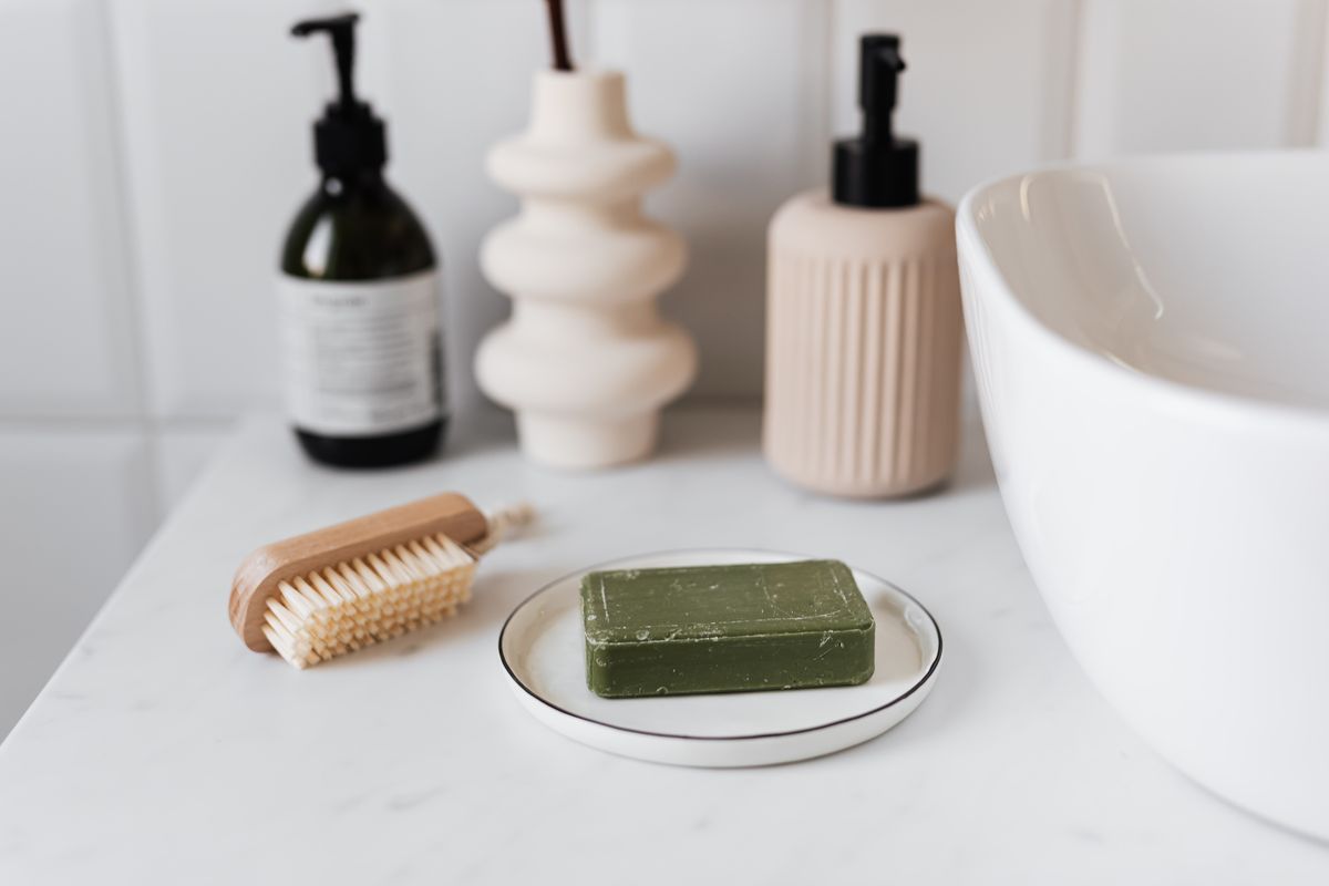 A calm bathroom counter with soap, a brush and skincare bottles