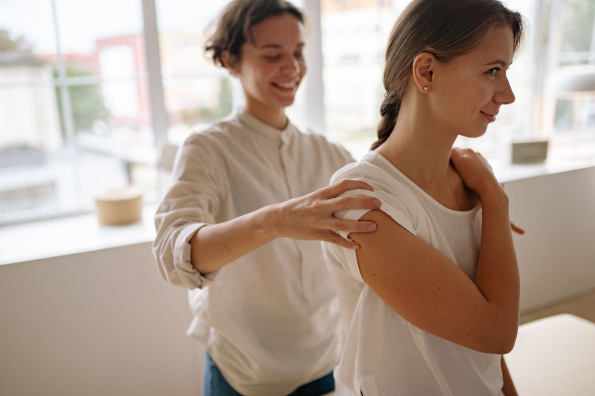 A therapist assessing a woman's shoulder during a physiotherapy appointment