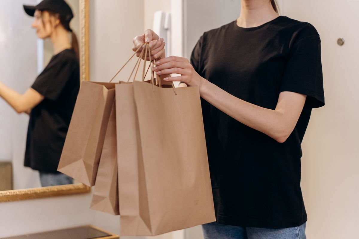 A woman carrying paper shopping bags by the handles, the same load transfer that causes bra strap grooves