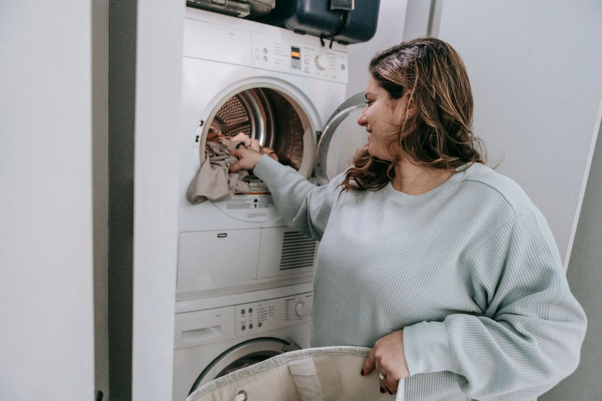 A woman loading laundry into a washing machine at home