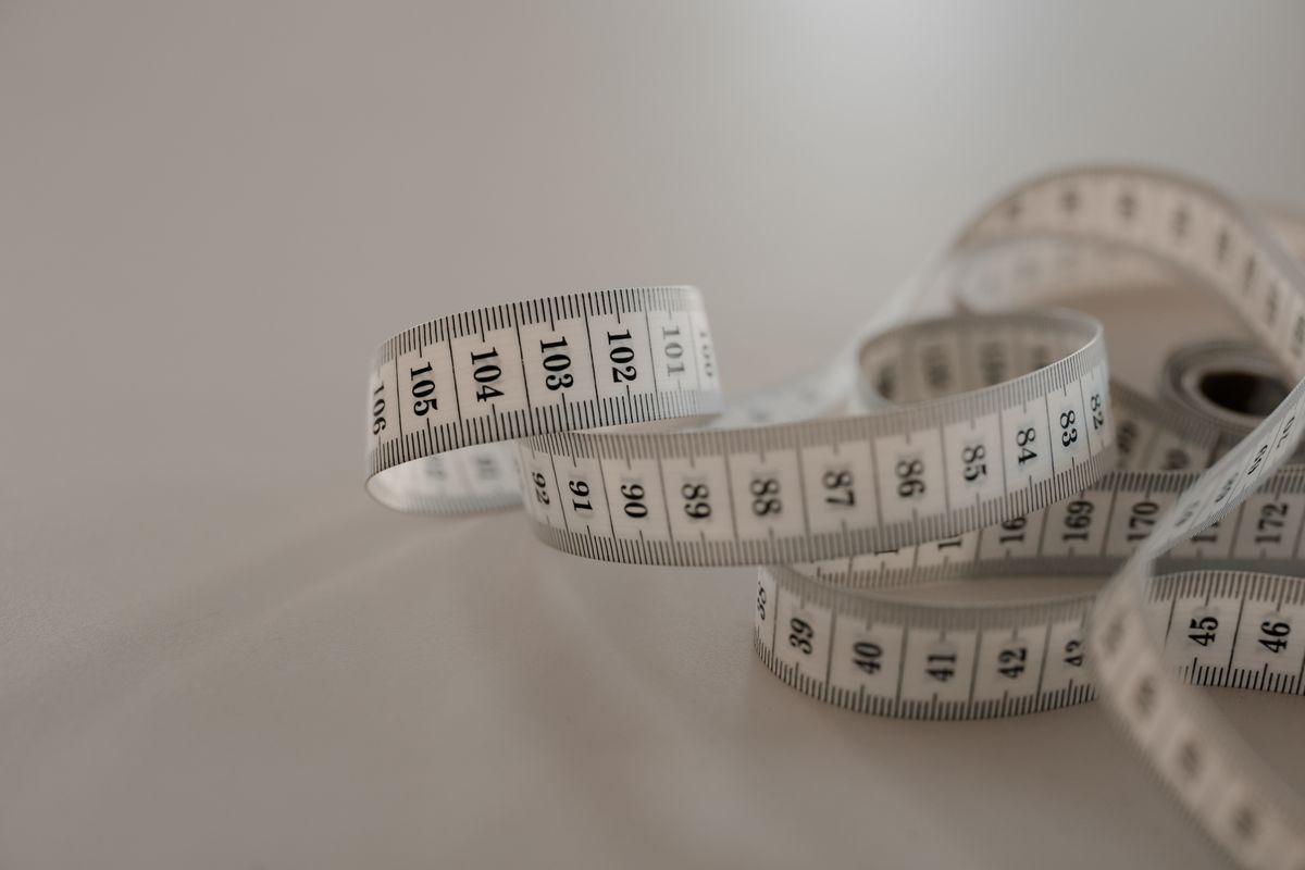 Close-up of hands measuring around the body with a soft tape, showing how to measure bra size at home
