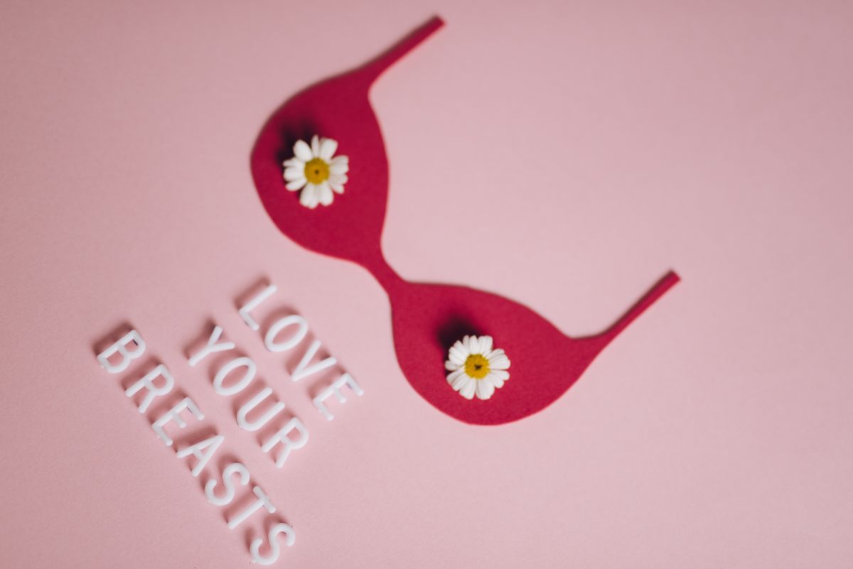 Pink flat lay with a bra shape and daisies, a reminder to recheck your bra size and breast health
