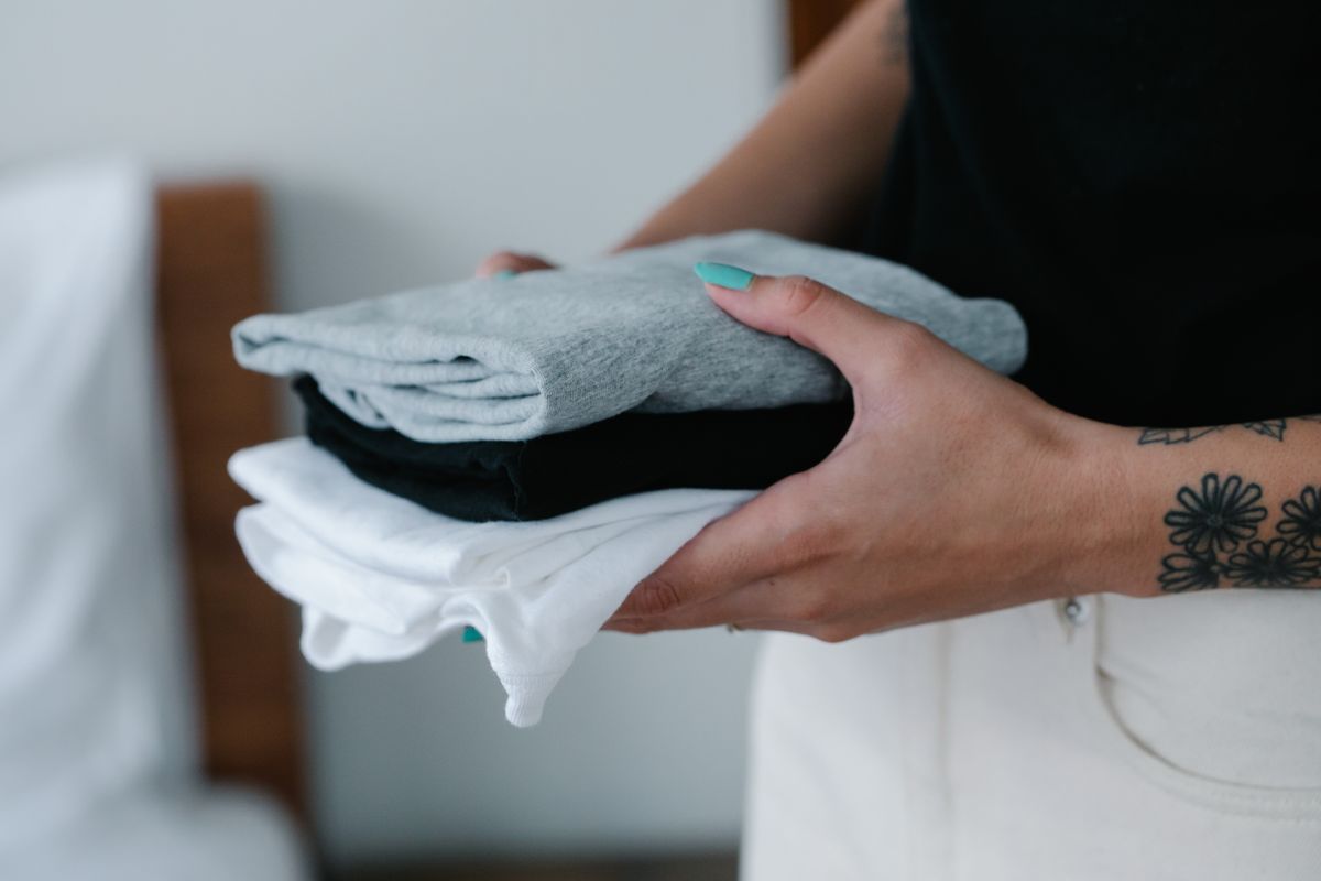 Hands holding a small stack of neatly folded clothes, sorting what to keep