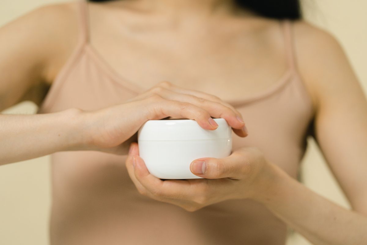 Close-up of hands applying moisturiser, part of caring for skin marked by a bra